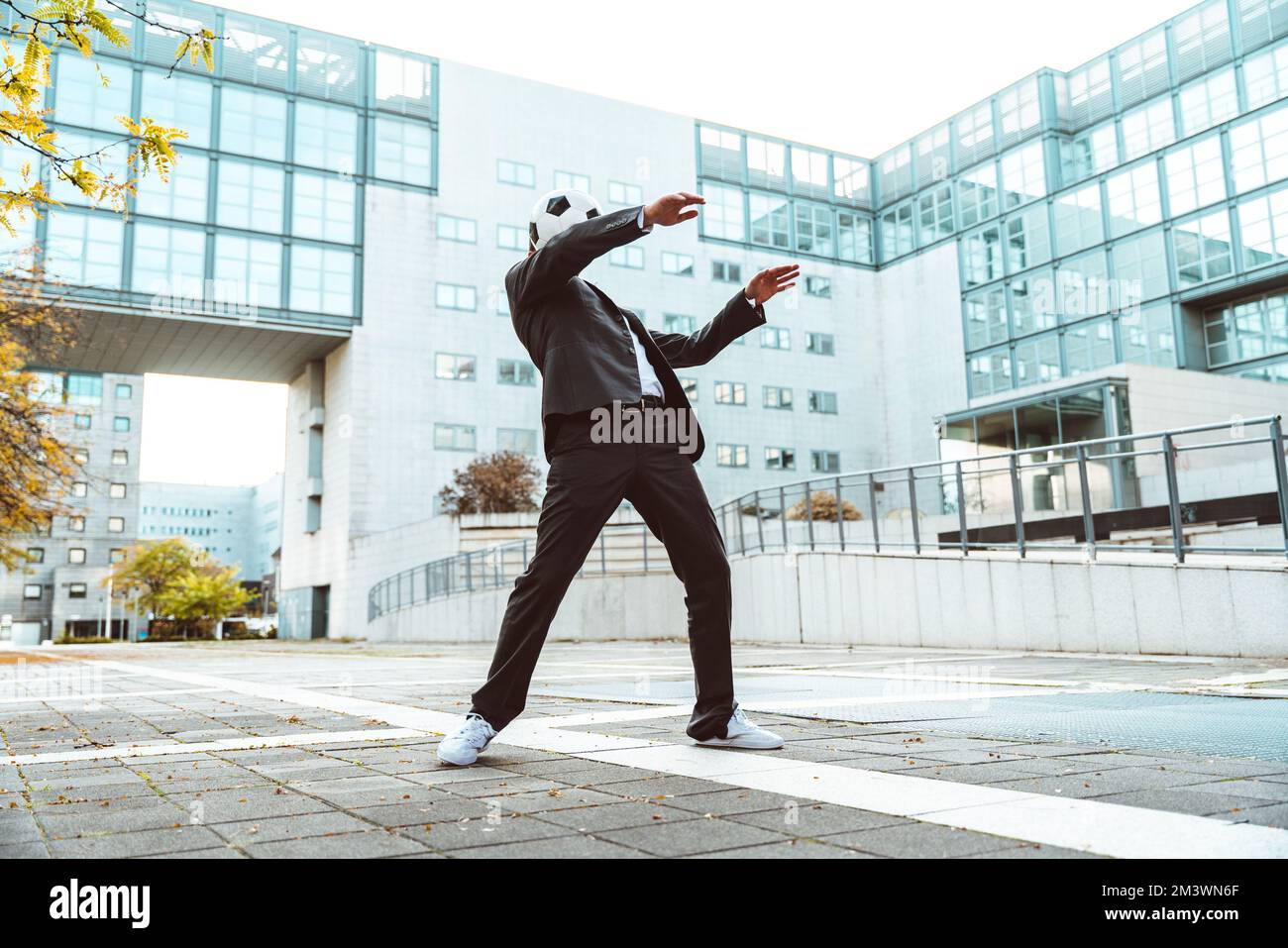 Bild eines Geschäftsmanns und Freispielers, der mit dem Ball auf der Straße Tricks macht. Konzept über Sport- und Geschäftsleute Stockfoto