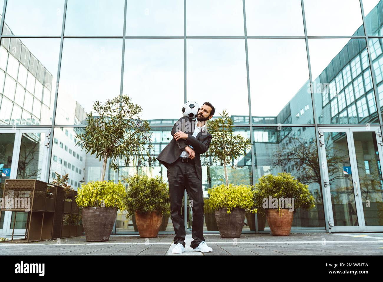 Bild eines Geschäftsmanns und Freispielers, der mit dem Ball auf der Straße Tricks macht. Konzept über Sport- und Geschäftsleute Stockfoto