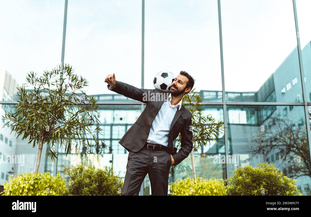 Bild eines Geschäftsmanns und Freispielers, der mit dem Ball auf der Straße Tricks macht. Konzept über Sport- und Geschäftsleute Stockfoto