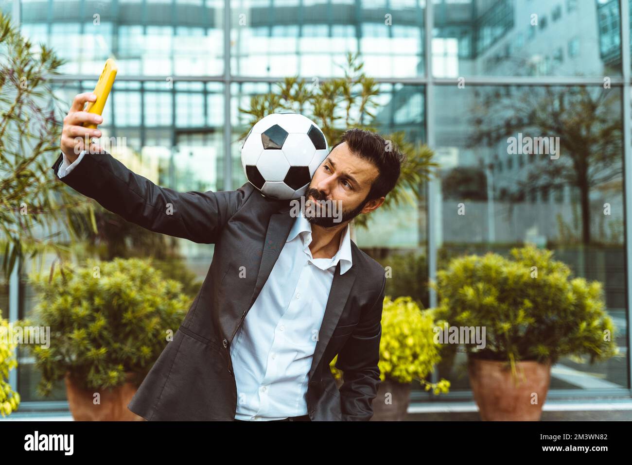 Bild eines Geschäftsmanns und Freispielers, der mit dem Ball auf der Straße Tricks macht. Konzept über Sport- und Geschäftsleute Stockfoto