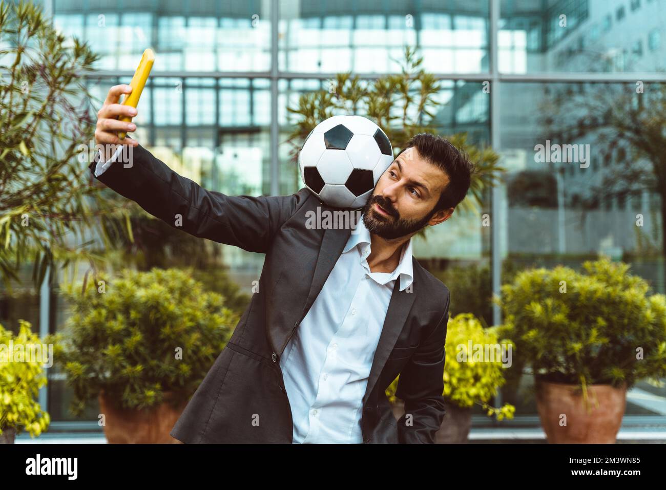 Bild eines Geschäftsmanns und Freispielers, der mit dem Ball auf der Straße Tricks macht. Konzept über Sport- und Geschäftsleute Stockfoto