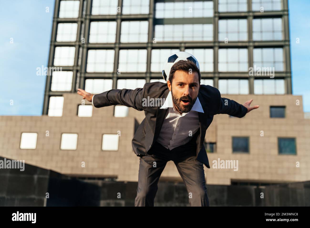 Bild eines Geschäftsmanns und Freispielers, der mit dem Ball auf der Straße Tricks macht. Konzept über Sport- und Geschäftsleute Stockfoto