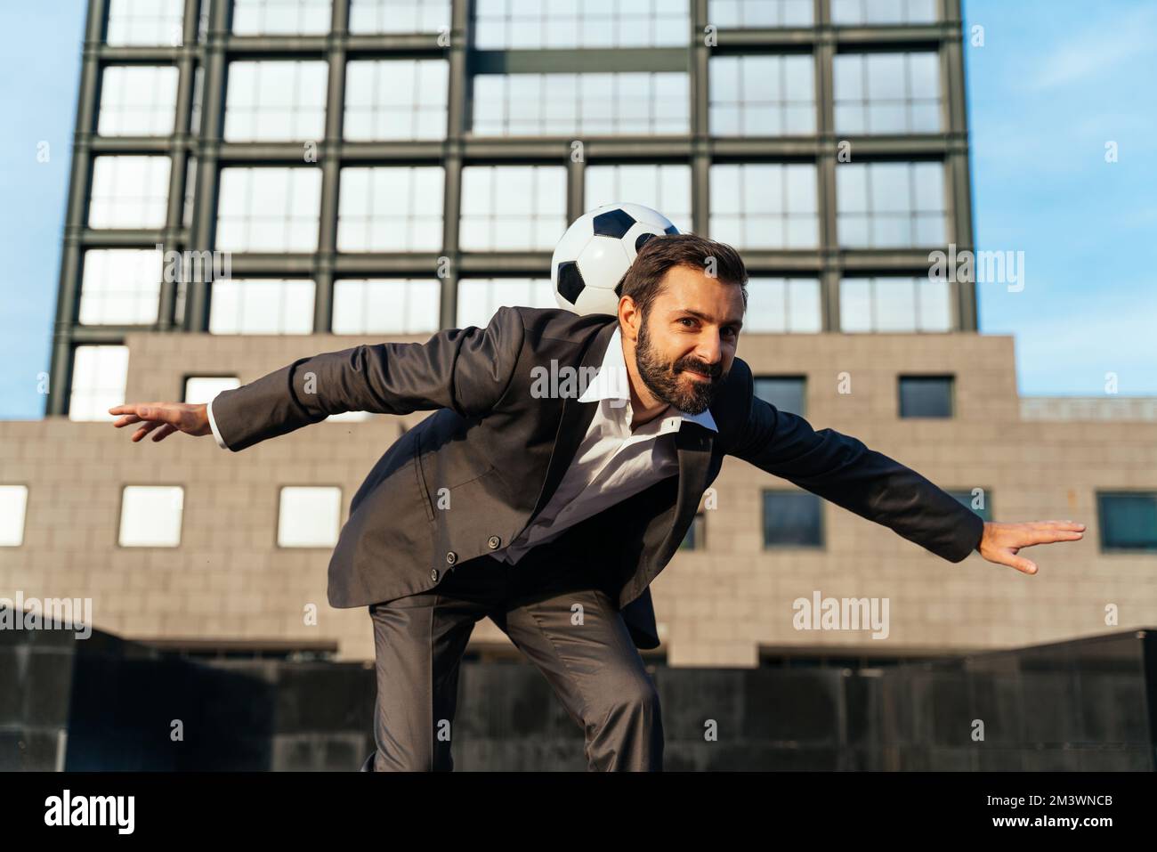 Bild eines Geschäftsmanns und Freispielers, der mit dem Ball auf der Straße Tricks macht. Konzept über Sport- und Geschäftsleute Stockfoto