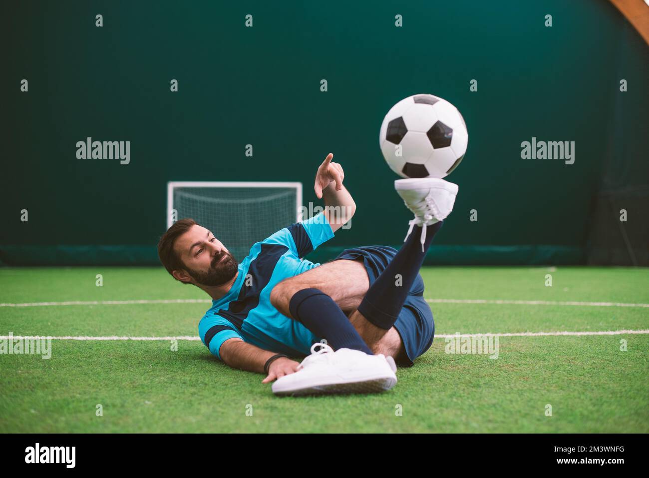 Filmbild eines Freistil-Fußballspielers, der auf einem Kunstrasen-Spielplatz mit dem Ball Tricks macht. Konzept über Sport und Lebensstil der Menschen Stockfoto