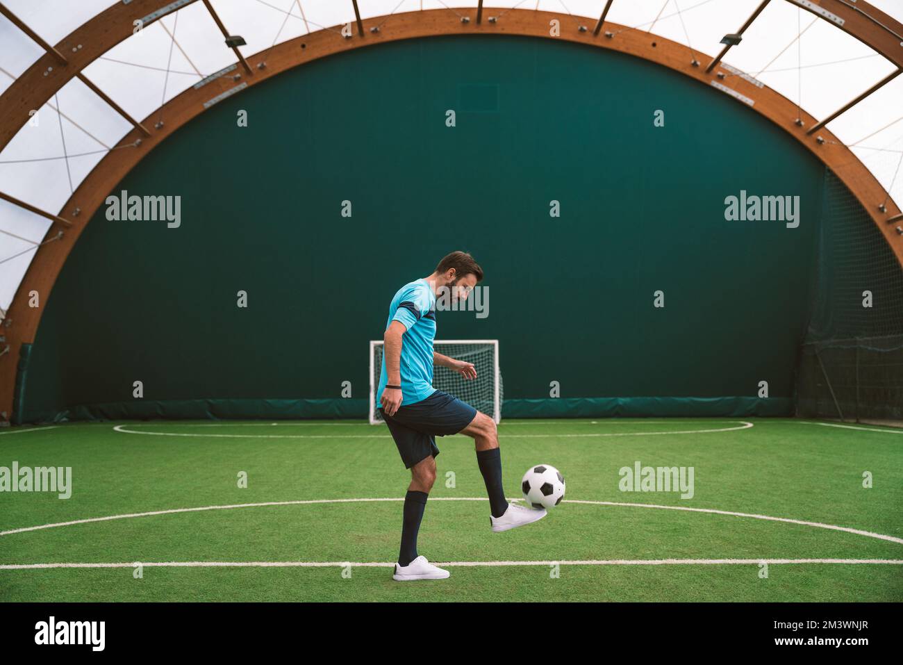 Filmbild eines Freistil-Fußballspielers, der auf einem Kunstrasen-Spielplatz mit dem Ball Tricks macht. Konzept über Sport und Lebensstil der Menschen Stockfoto