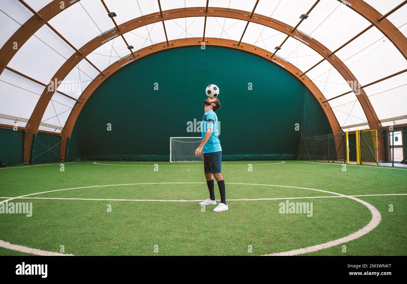 Filmbild eines Freistil-Fußballspielers, der auf einem Kunstrasen-Spielplatz mit dem Ball Tricks macht. Konzept über Sport und Lebensstil der Menschen Stockfoto