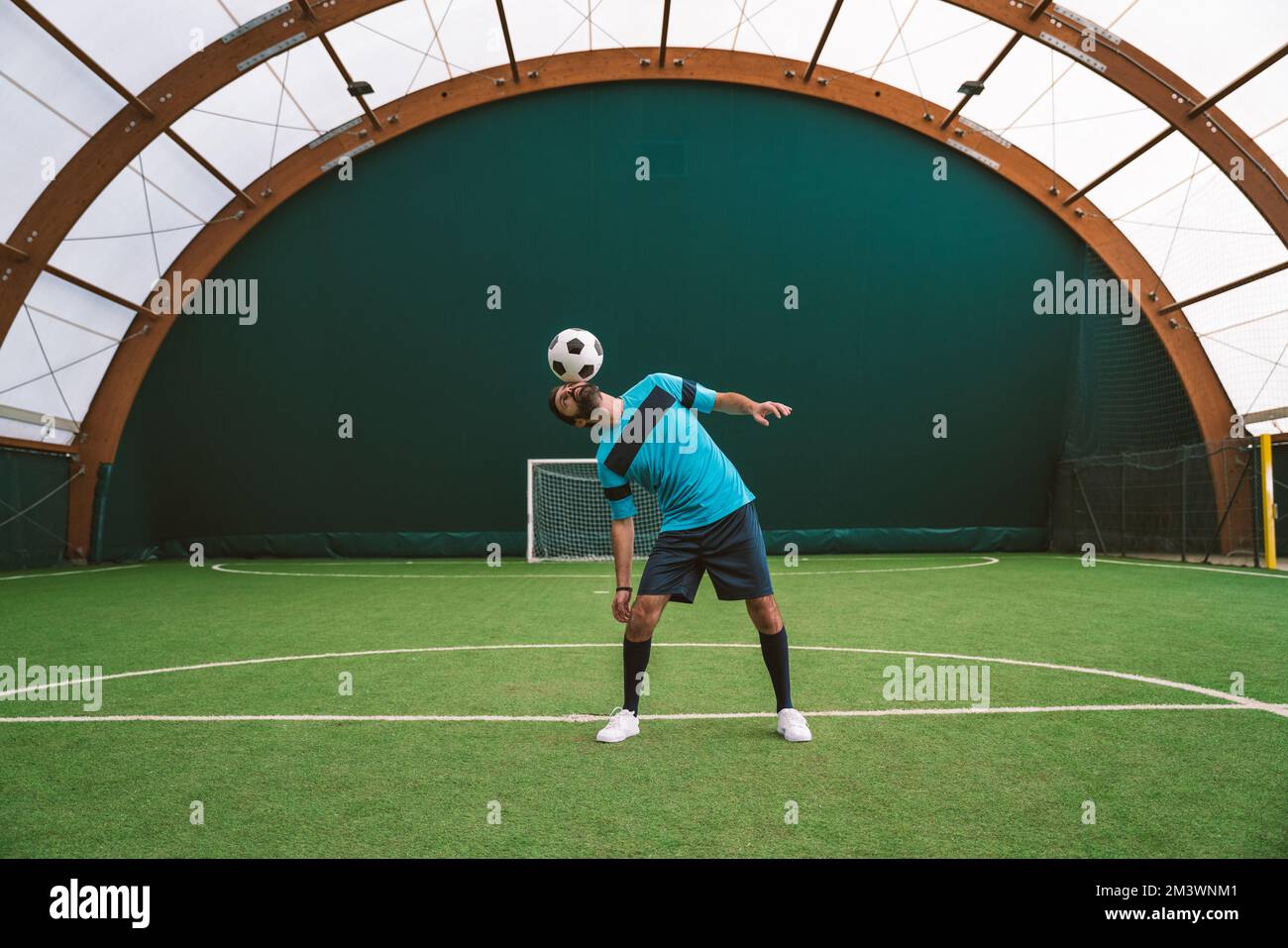 Filmbild eines Freistil-Fußballspielers, der auf einem Kunstrasen-Spielplatz mit dem Ball Tricks macht. Konzept über Sport und Lebensstil der Menschen Stockfoto