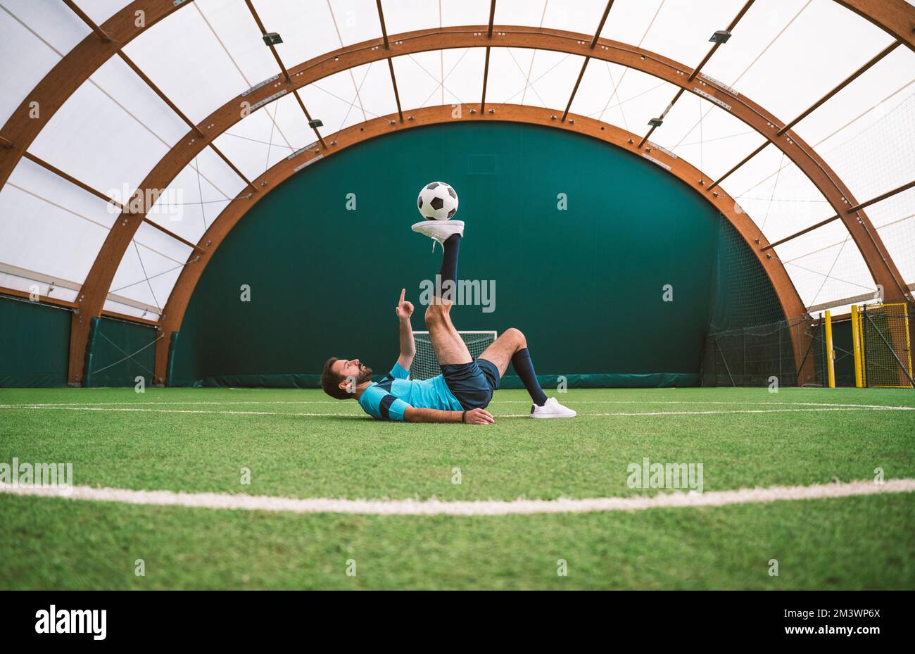 Filmbild eines Freistil-Fußballspielers, der auf einem Kunstrasen-Spielplatz mit dem Ball Tricks macht. Konzept über Sport und Lebensstil der Menschen Stockfoto