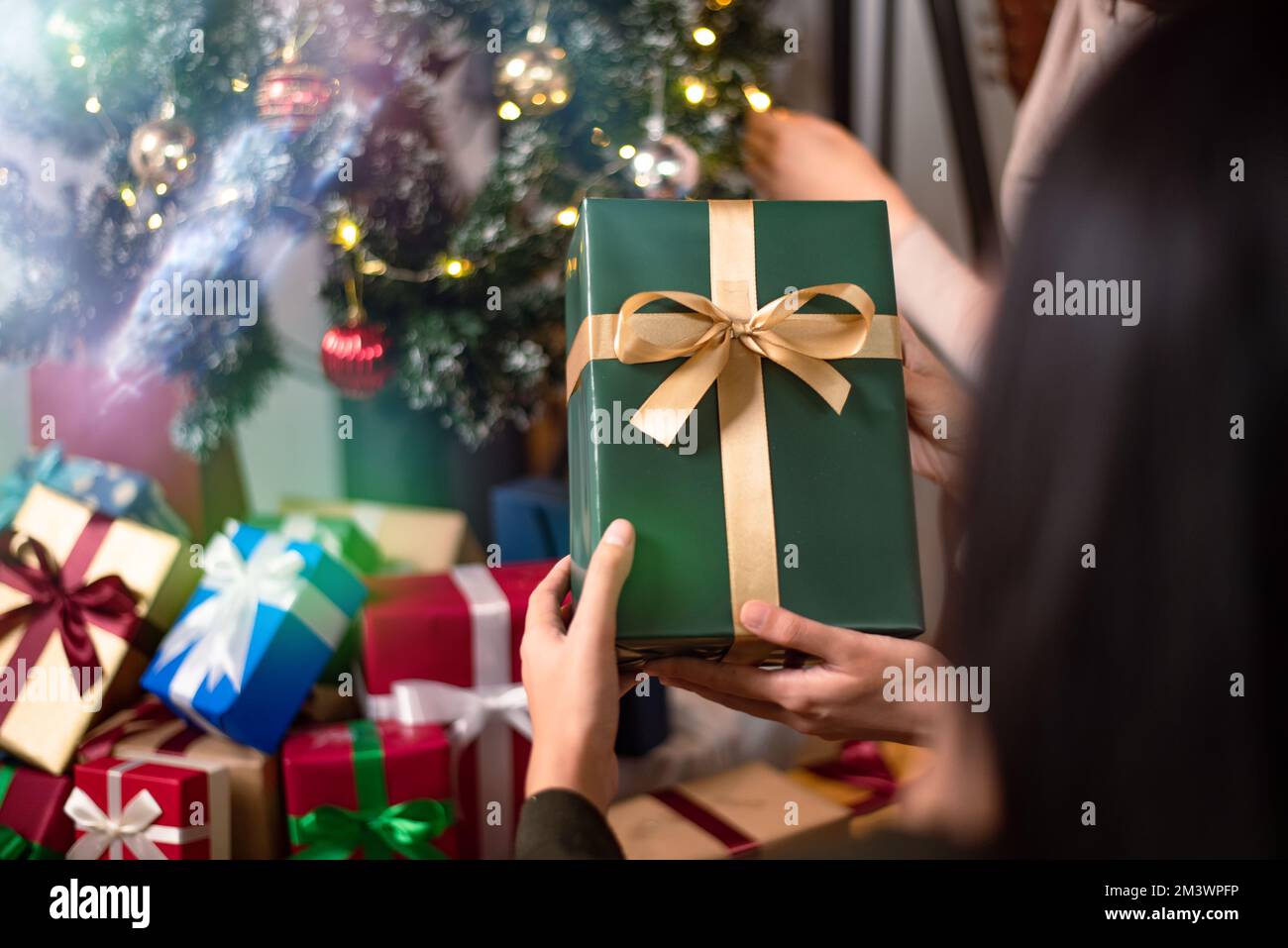 Frau mit Weihnachtsschmuck Geschenkbox-Nahaufnahme. Die Person schmückt den weihnachtsbaum in einem Haus für die Feiertagsfeier. Frohe Weihnachten Stockfoto