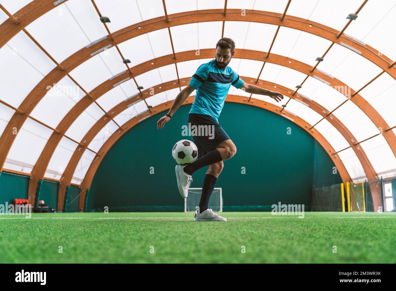 Filmbild eines Freistil-Fußballspielers, der auf einem Kunstrasen-Spielplatz mit dem Ball Tricks macht. Konzept über Sport und Lebensstil der Menschen Stockfoto