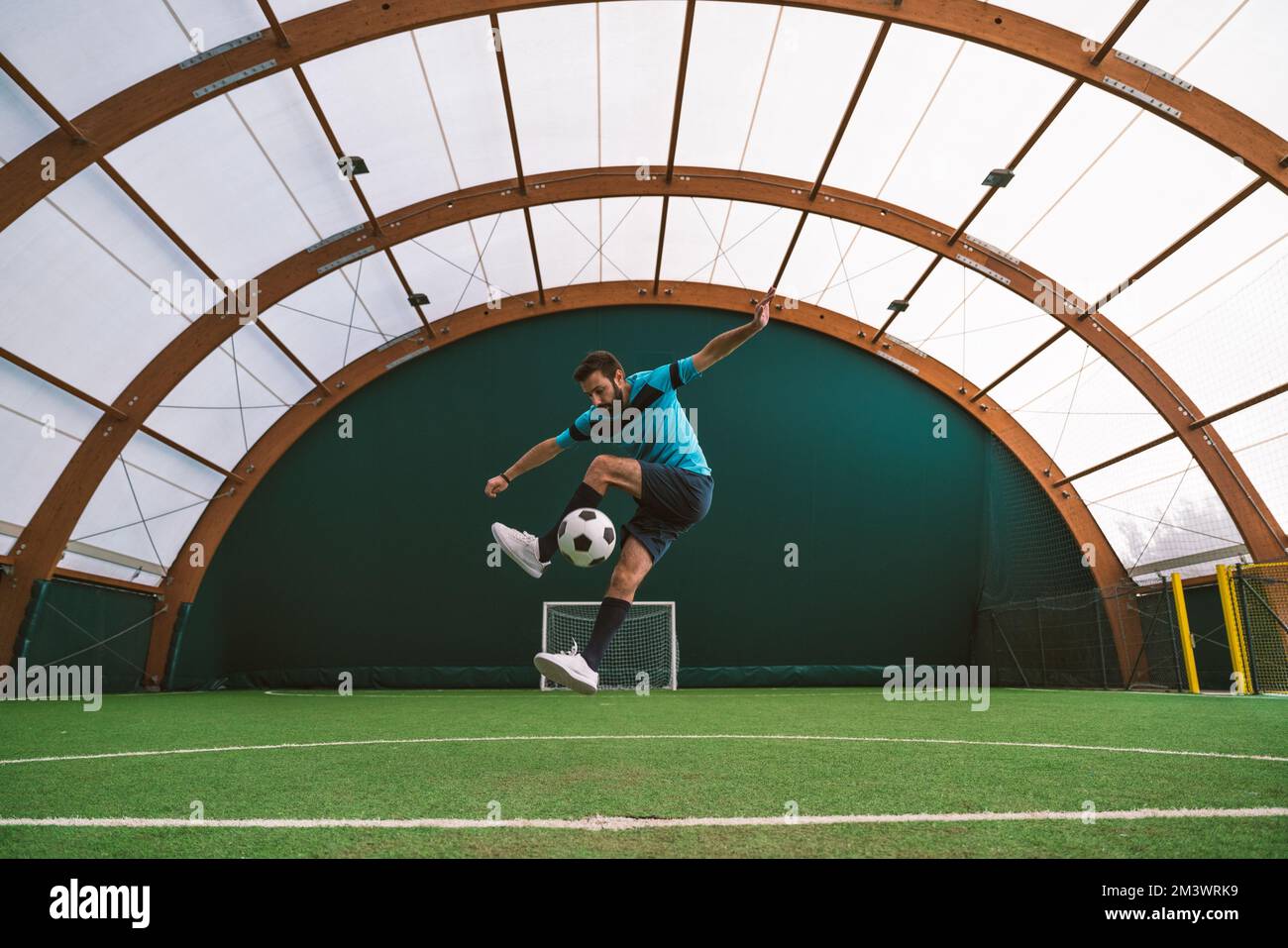 Filmbild eines Freistil-Fußballspielers, der auf einem Kunstrasen-Spielplatz mit dem Ball Tricks macht. Konzept über Sport und Lebensstil der Menschen Stockfoto