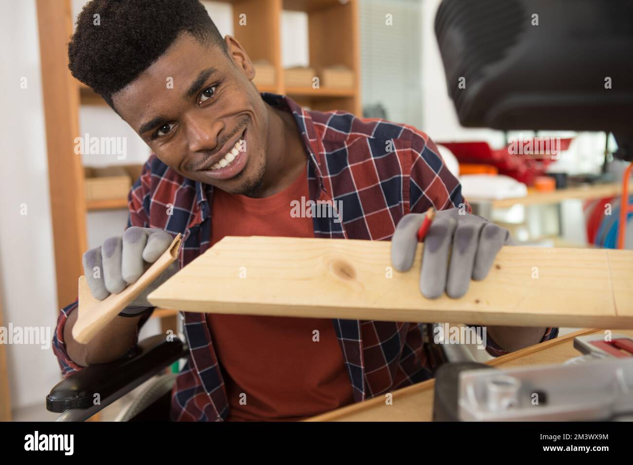 Junger Mann im Rollstuhl versucht sich selbst, sein Bücherregal zu falten Stockfoto