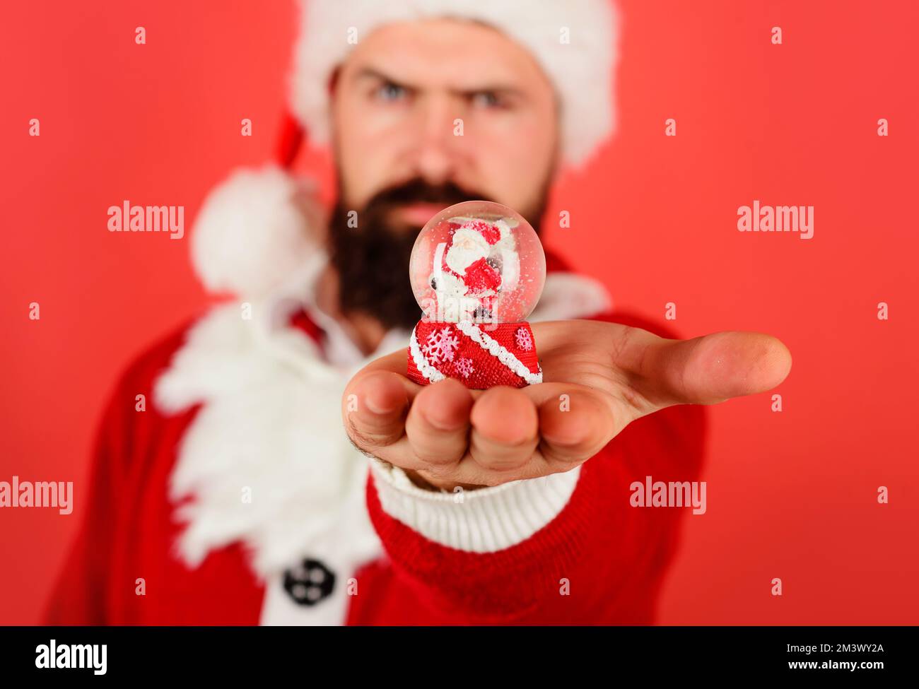 Weihnachtsschneekugeln in der Hand. Bärtiger Weihnachtsmann mit Schneeball. Dekorationselement. Selektiver Fokus. Stockfoto