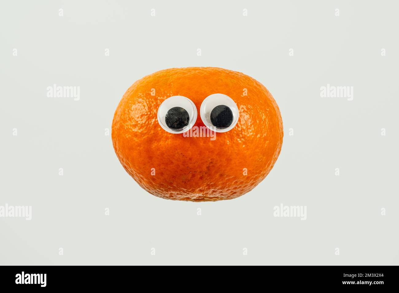 Einfache orangefarbene satsuma-Tangerine mit googly-Cartoon-Augen auf weißem Hintergrund Stockfoto