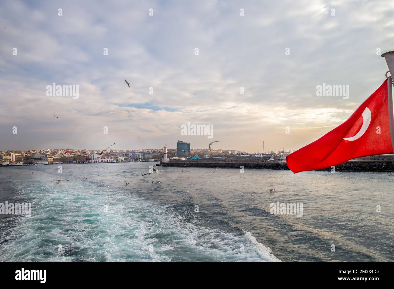 Wunderschöne Aussicht vom Passagierschiff auf das Kadikoy-Viertel von Istanbul mit Möwen und der roten türkischen Flagge. Pier auf der rechten Seite. Stockfoto