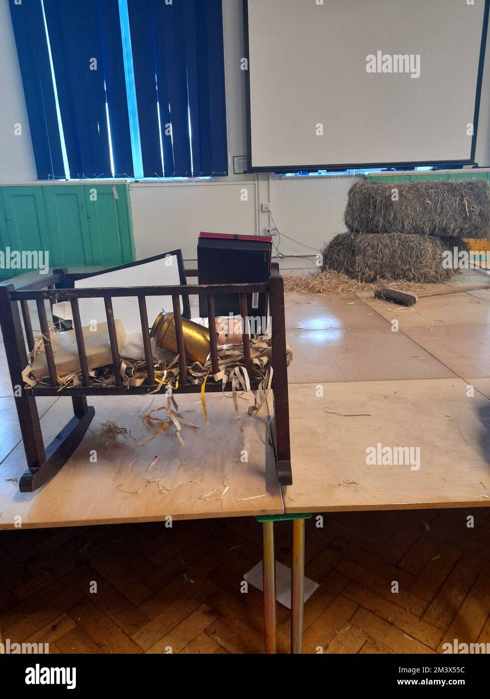 Die Nachwirkungen eines Krippenspiels in einer englischen Schule mit Requisiten, die unzeremoniell in das Kinderbett auf dem Jesus-Baby gelegt wurden Stockfoto