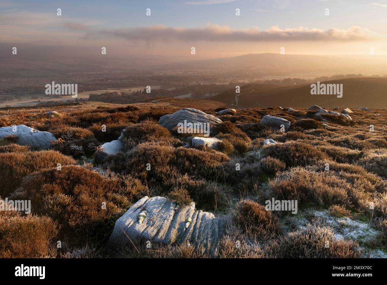 Frostbedeckte Felsen im Moor mit Blick auf Burley-in-Wharfedale in West Yorkshire, Großbritannien Stockfoto