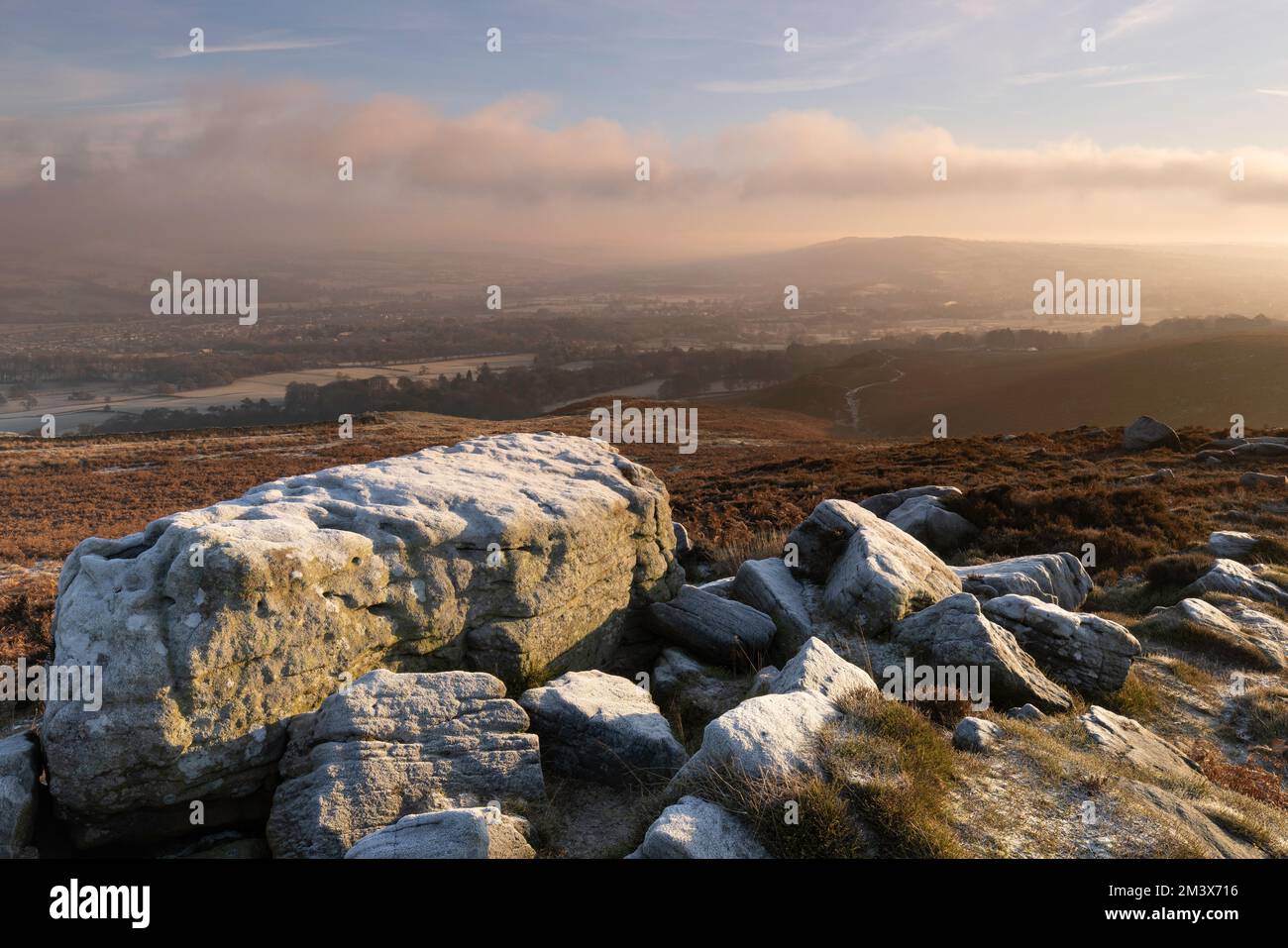 Frostbedeckte Felsen im Moor mit Blick auf Burley-in-Wharfedale in West Yorkshire, Großbritannien Stockfoto