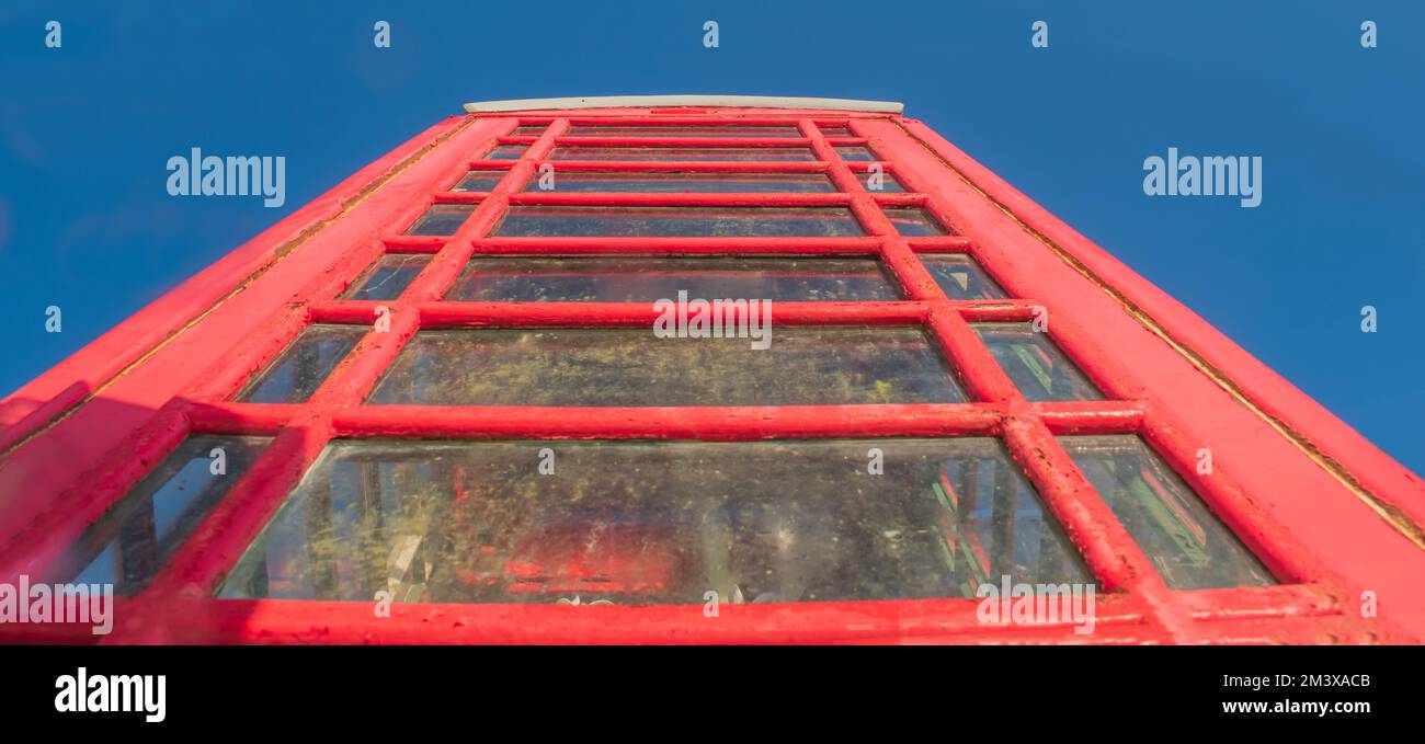 Von der Basis einer roten britischen Telefonzelle zu einem blauen Himmel aufblickend Stockfoto