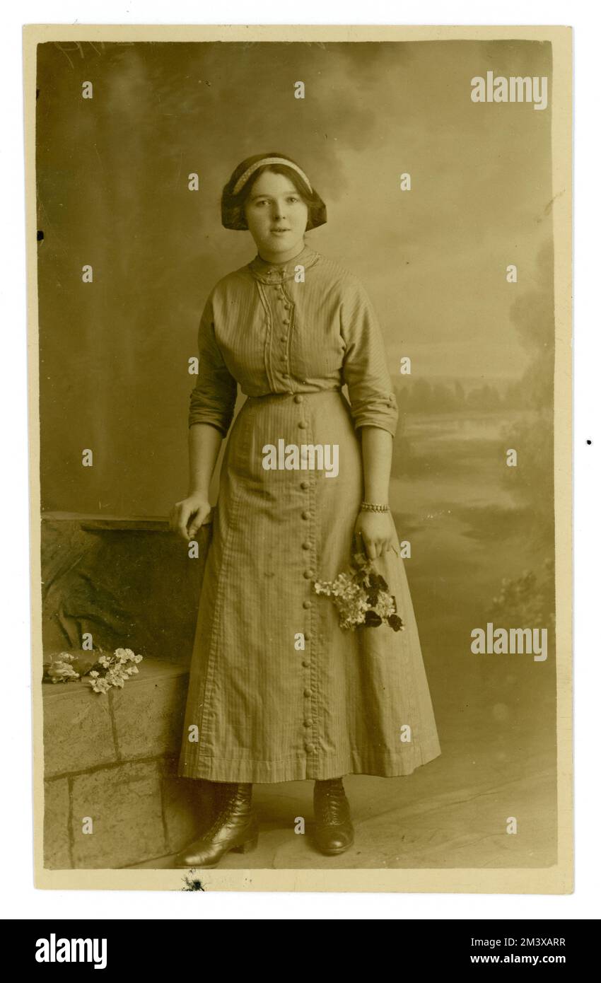 Originale Postkarte aus der WW1. Epoche mit attraktivem Mädchen/jungen Frau aus der Teenagerzeit, die eine Bluse und einen langen Rock trägt, einen Saum direkt über ihrem Knöchel, ihr Haar scheint in einer Schleife auf der Rückseite gebunden zu sein, möglicherweise ihr erstes Erwachsenenfoto. UK, ca. 1915. Stockfoto