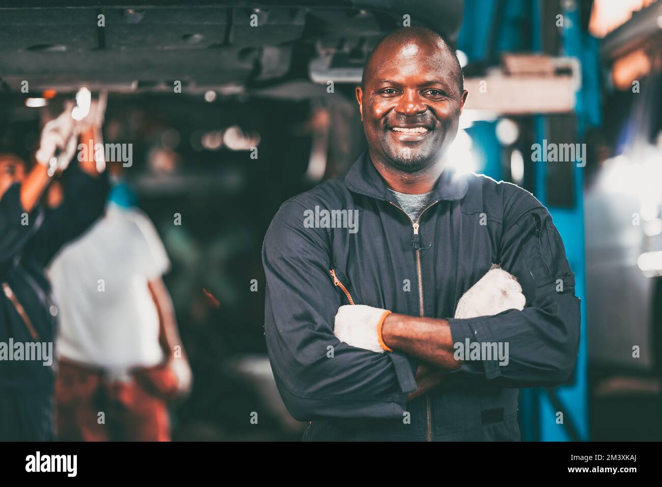 Porträt Garagenmechaniker professioneller Arbeiter Automotor Service sieht Kamera Lächeln Arm gekreuzt Stockfoto