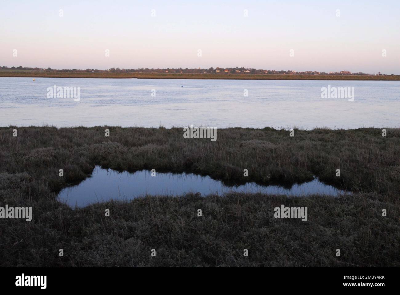 Reflexionen im Wasserpool von Salinen bei Flut mit Küstensümpfen und der Stadt Aldeburgh in der Ferne. ALDE Ore Estuary, 25. November 2022 Stockfoto