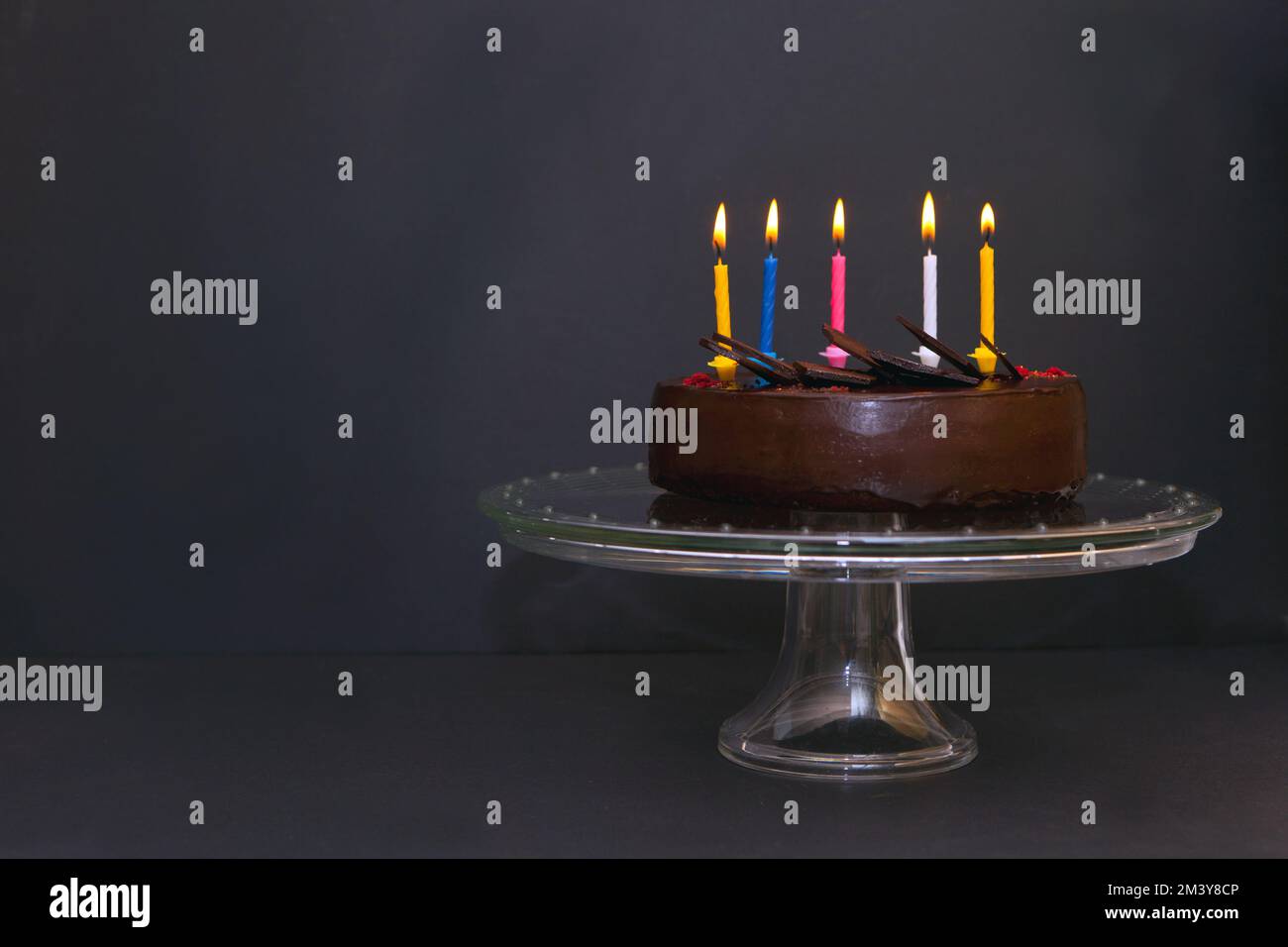 Schokoladenkuchen mit fünf bunten Kerzen. Geburtstagskuchen mit Kerzenlicht Stockfoto