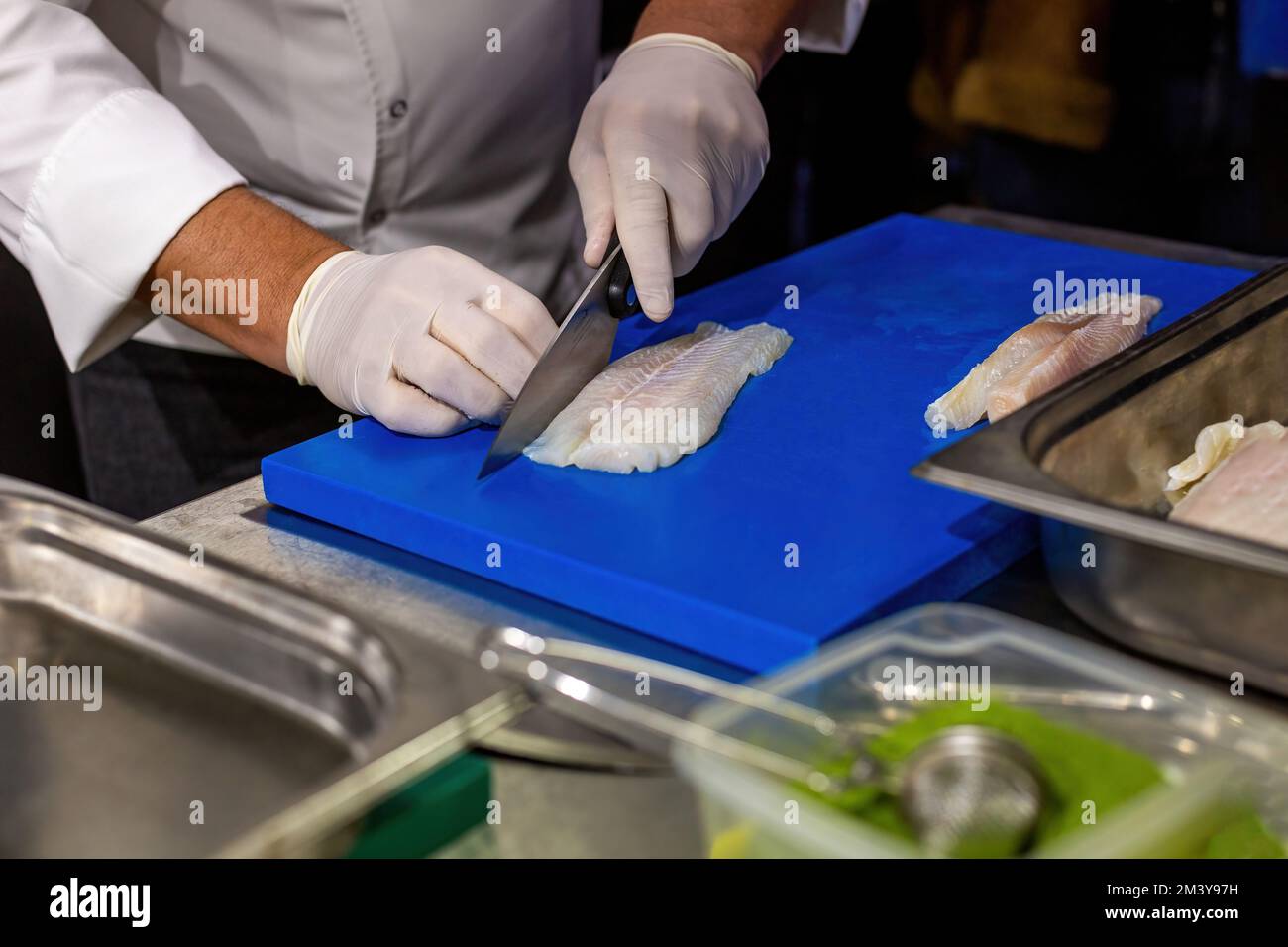 Der Koch hackt die Seezunge. Den Fisch mit einem Messer schneiden. Stockfoto