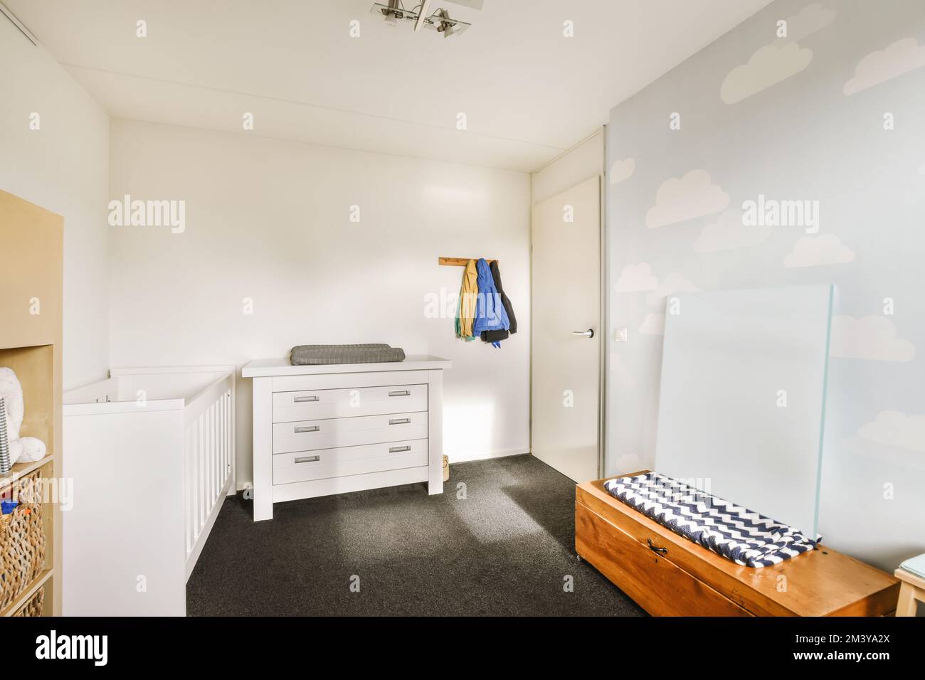 Ein Zimmer mit Bett, Kommode und Spiegel an der Wand dahinter ist eine weiße Schranktür mit blauem Schachtel Stockfoto