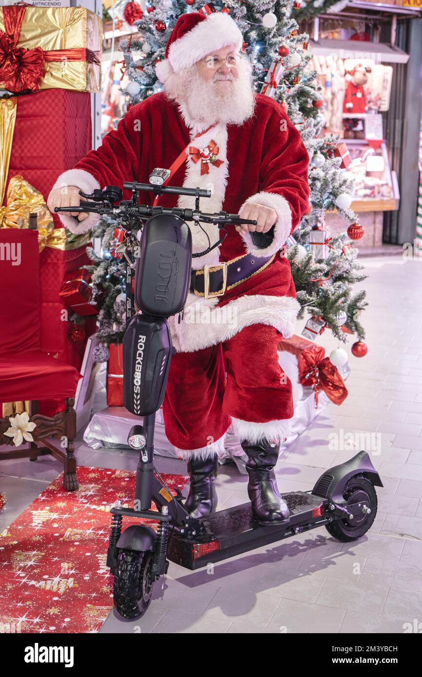 Der Weihnachtsmann mit Weihnachtsmütze kleidet roten Anzug, der auf dem Roller steht, mit Geschenken. Mailand, Italien - Dezember 2022 Stockfoto
