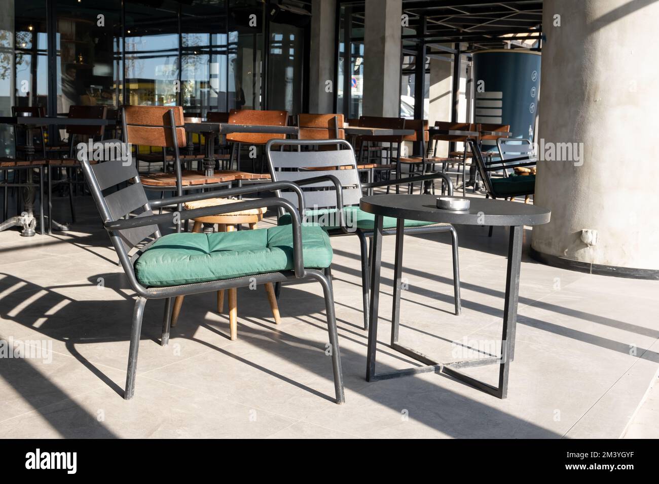 Leere Stühle und Tische aus Metall vor dem Café. Zwei leere Metallstühle und ein Tisch Stockfoto