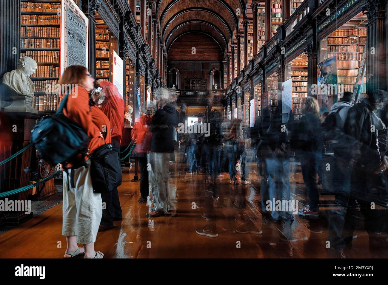 Alte Bibliothek aus dem 18.. Jahrhundert, Menschenmenge zwischen Büstenregalen und Büsten im Long Room, lange Exposition, Trinity College, Universität Dublin, Irland Stockfoto