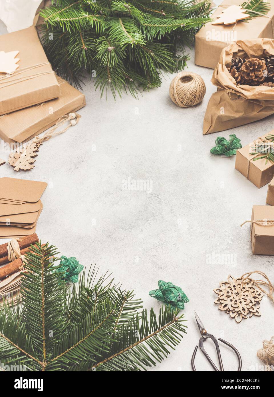 Umweltfreundlicher Weihnachtsrahmen ohne Abfall. Weihnachtsbaum Zweige in Baumwollbeutel, Geschenke in braunem Papier, Kiefernzapfen Anhänger hessische Zimtstäbchen zum Dekorieren von Boxen. Draufsicht, getönt, selektiver Fokus Stockfoto