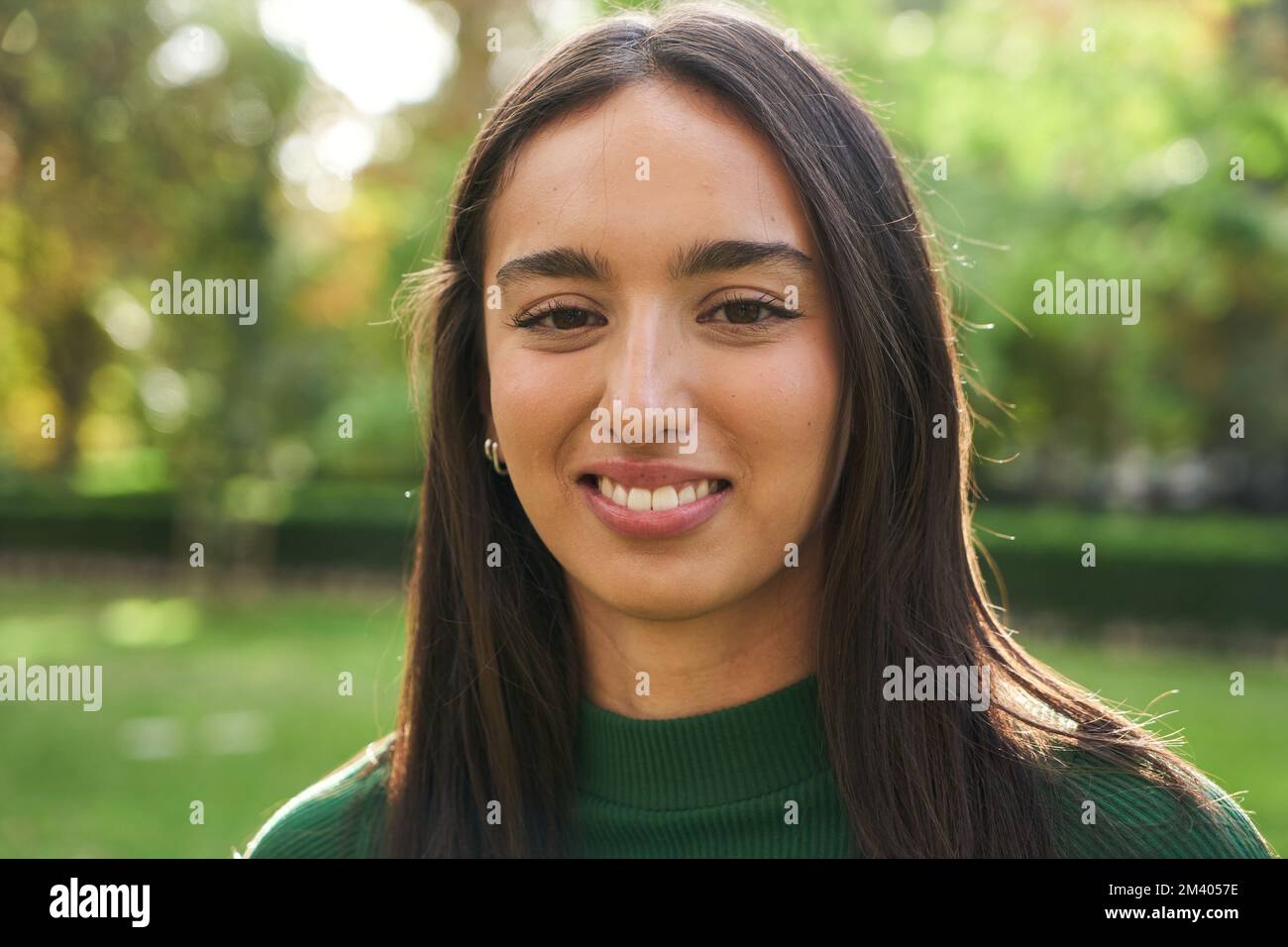 Porträt einer jungen, hübschen, weißen Frau, die lächelt und draußen vor die Kamera schaut Happy Chinese girl. Stockfoto