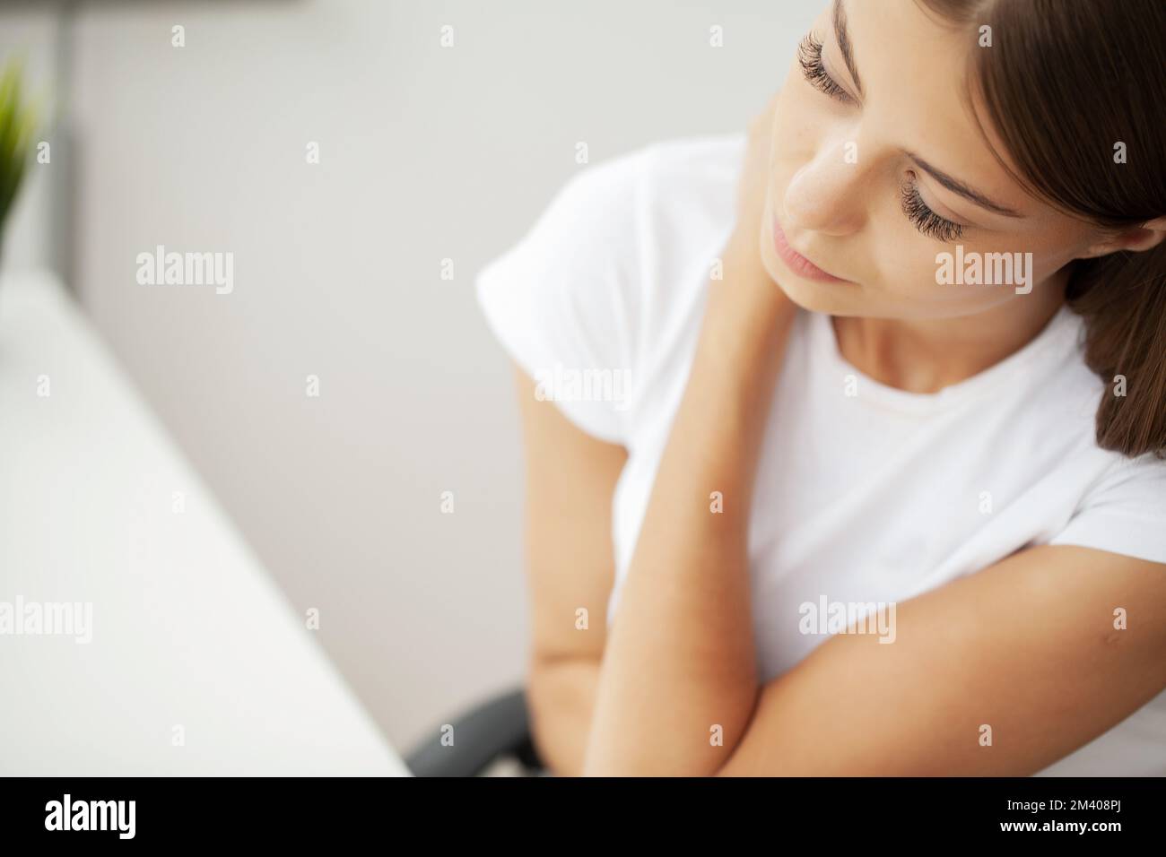 Brünette Frau hat Nackenschmerzen im Büro. Stockfoto