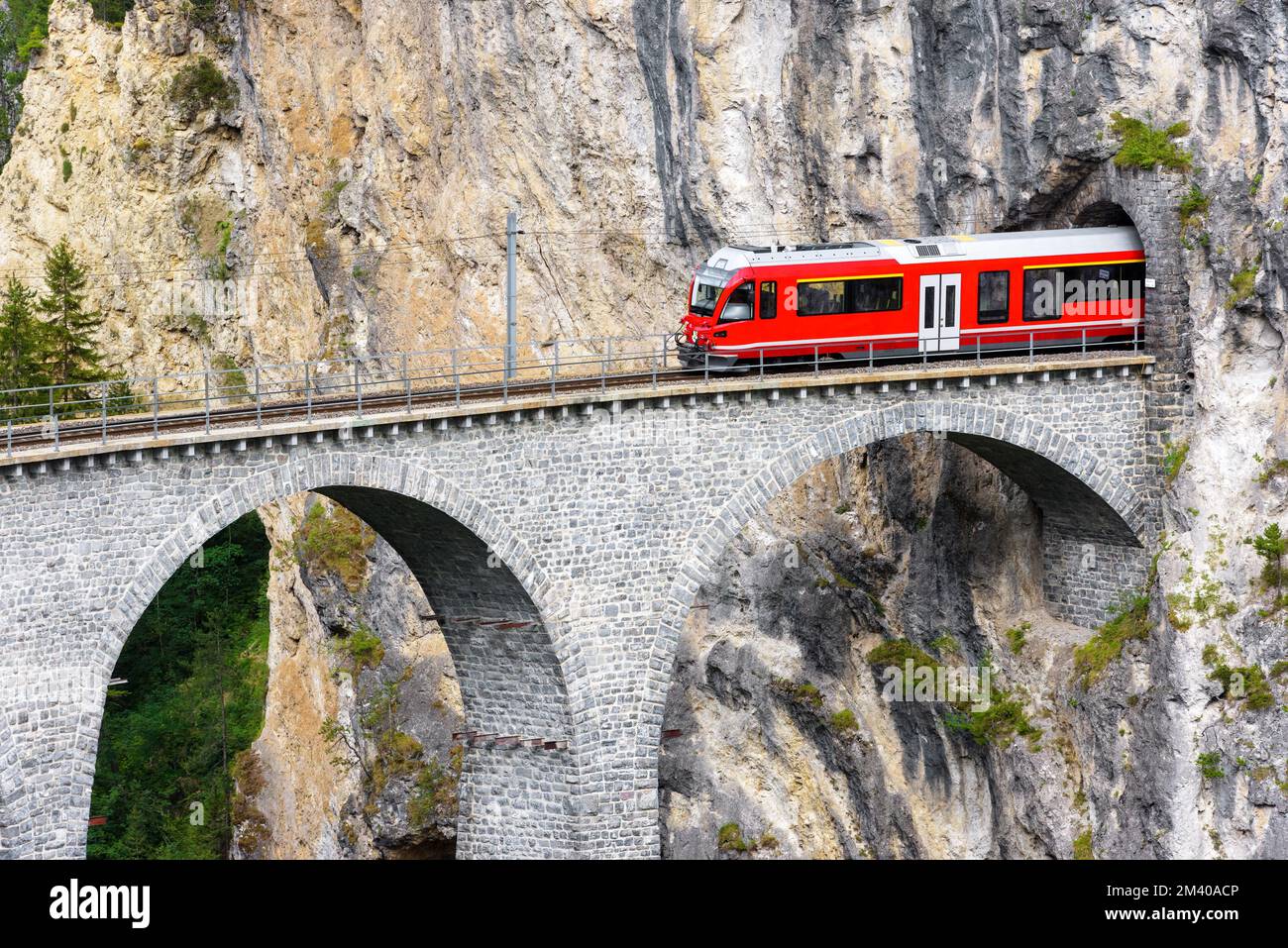 BERNINA Express Gletscherzug auf Landwasser Viadukt, Filisur, Schweiz. Blick auf die hohe Eisenbahnbrücke und den Tunnel im Fels der Schweizer Alpen. mou-Thema Stockfoto