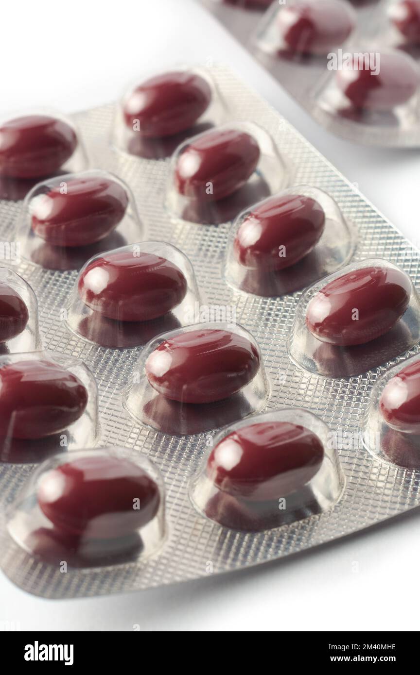 Nahaufnahme von roten Eisentabletten in Blisterpackungen, Vitaminpillen zur Verbesserung des Eisenspiegels im Blut, medizinische Medikamentenpakete im selektiven Fokus auf weiß Stockfoto