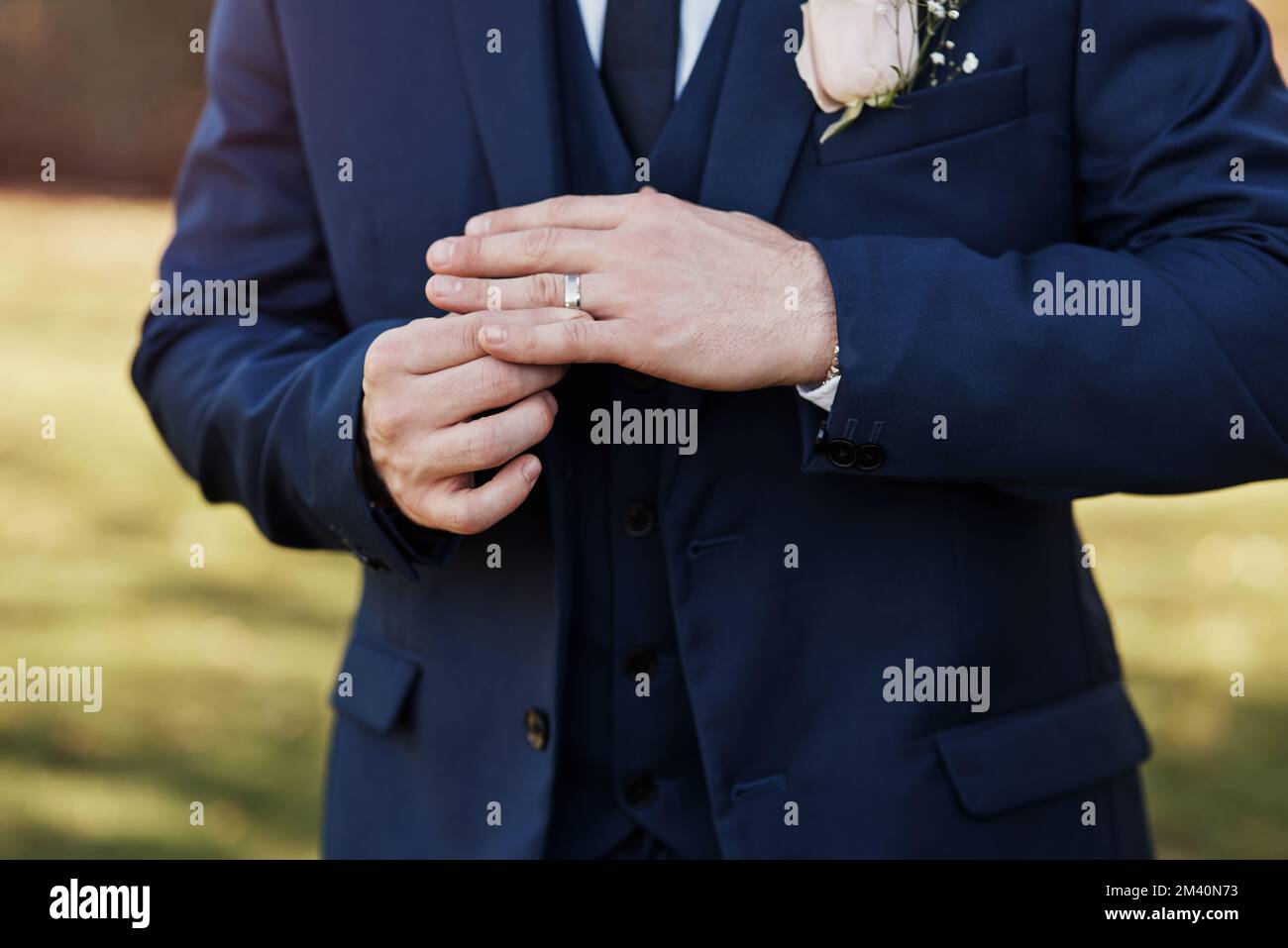 Er trägt diesen Schmuck, um sein Engagement zu zeigen. Ein nicht wiedererkennbarer Bräutigam, der seinen Ring an seinem Hochzeitstag justiert. Stockfoto