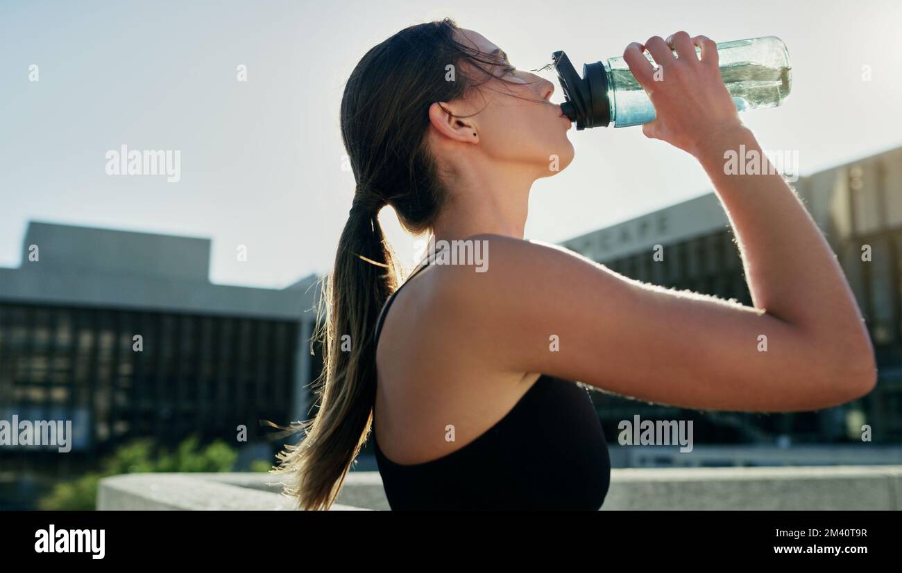 Nichts erfrischt besser als Wasser. Eine junge Frau, die während ihres Trainings in der Stadt Wasser trinkt. Stockfoto
