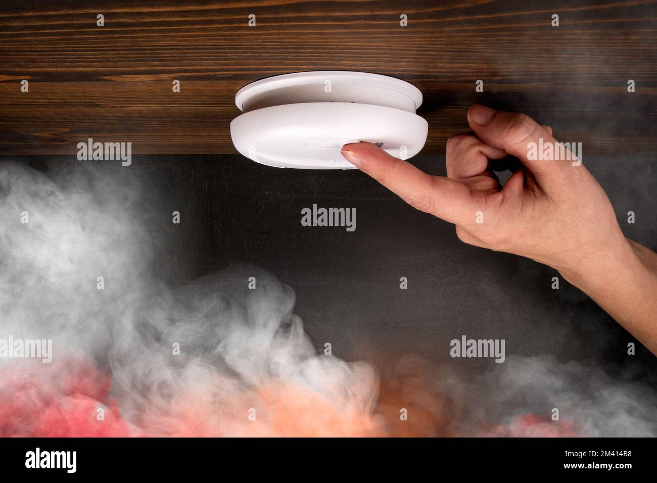Weißer Rauchmelder und Frauenhand. Bunter Rauch. Stockfoto