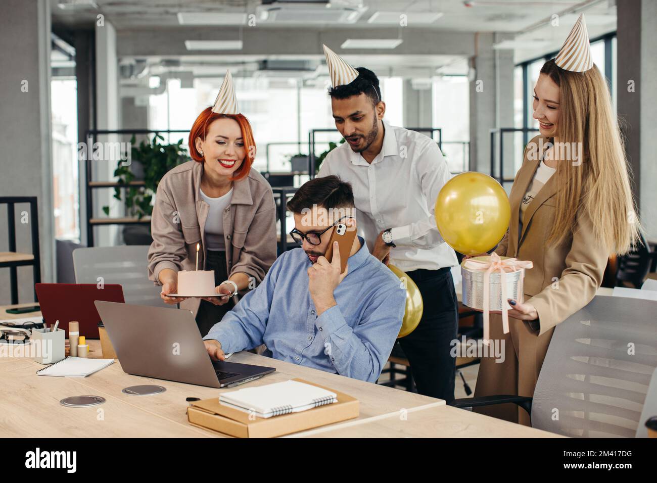 Überraschung. Gemischte Rassen glückliche Menschen feiern den Geburtstag eines Kollegen in einem modernen Büro Stockfoto