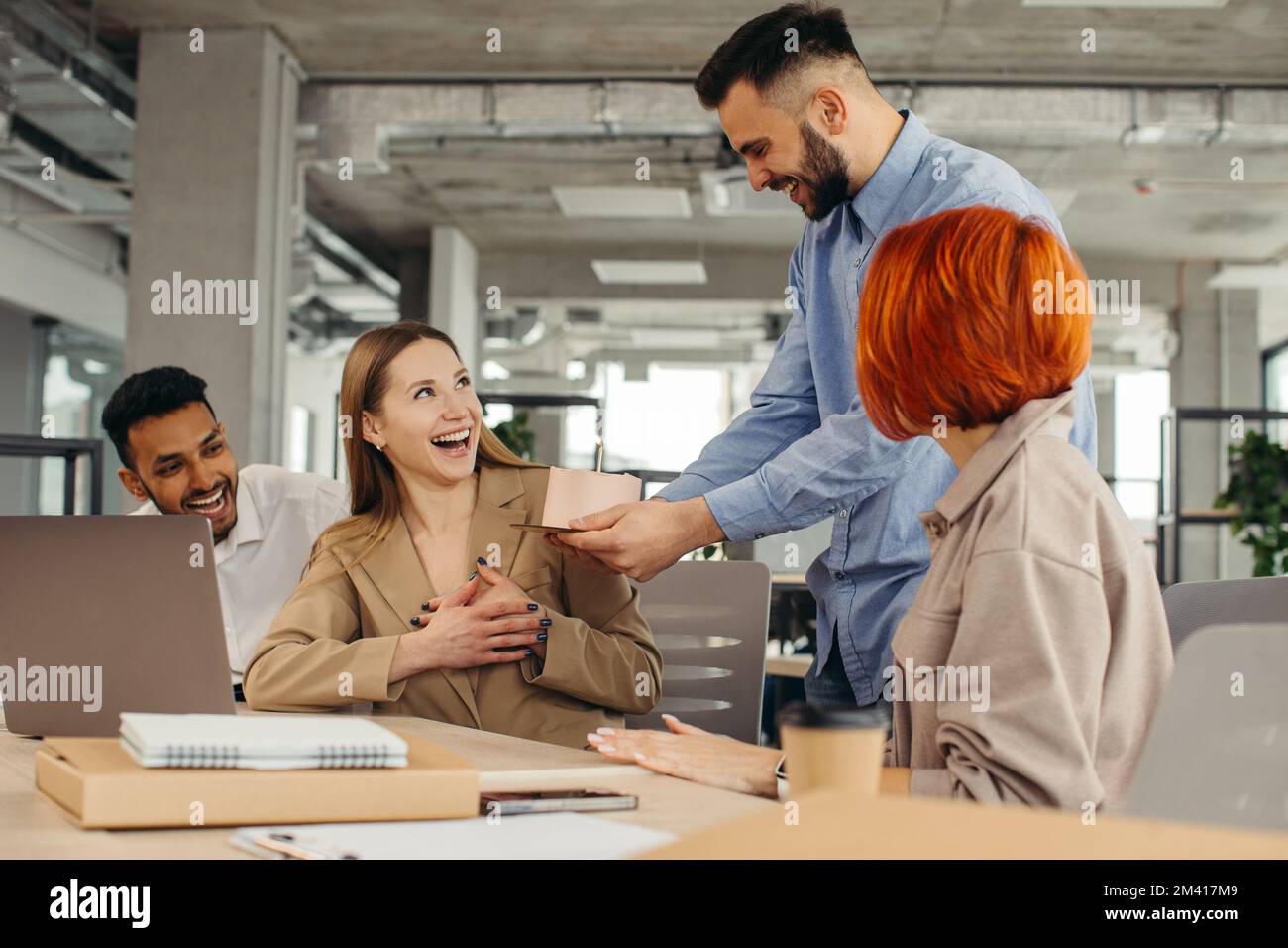 Das Business-Team feiert den Geburtstag eines Kollegen mit einem Kuchen im Büro. Den Geburtstag eines Mitarbeiters am Arbeitsplatz feiern. Stockfoto