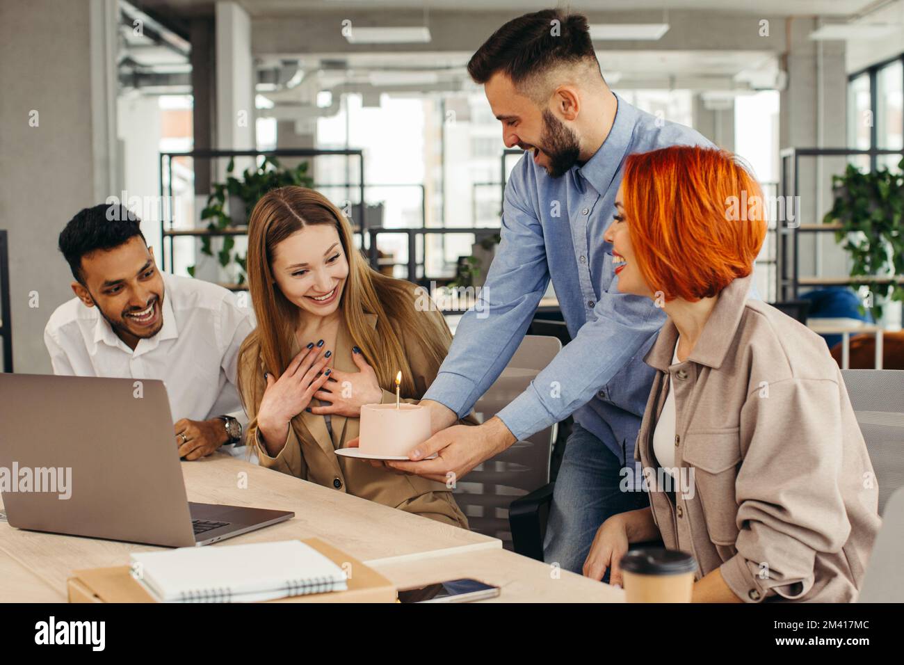 Das Business-Team feiert den Geburtstag eines Kollegen mit einem Kuchen im Büro. Den Geburtstag eines Mitarbeiters am Arbeitsplatz feiern. Stockfoto