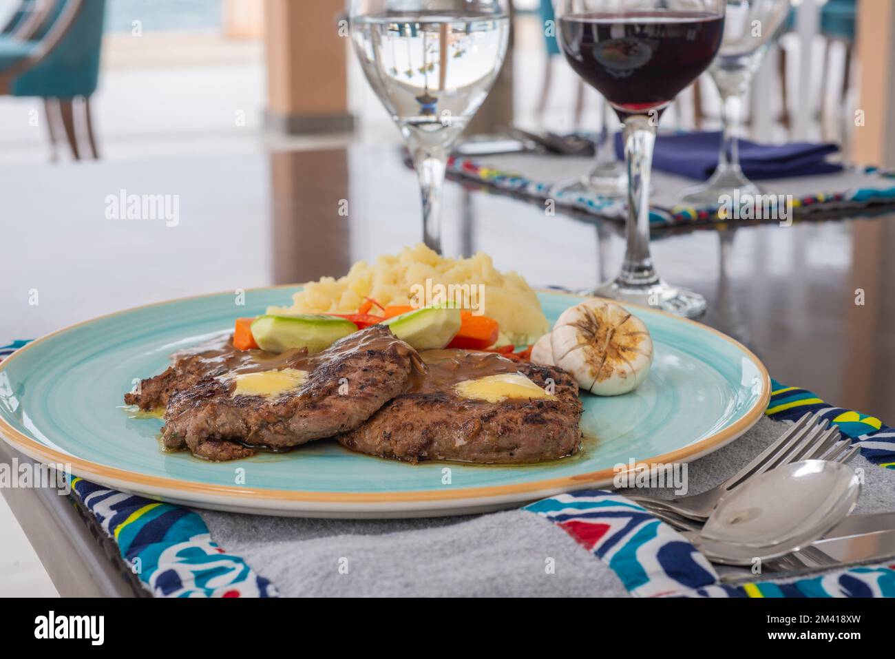 A-la-Carte-Steak mit Pfeffersauce auf blauem Teller mit Gemüse am Restauranttisch Stockfoto