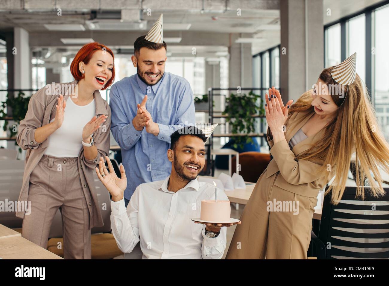 Überraschung. Gemischte Rassen glückliche Menschen feiern den Geburtstag eines Kollegen in einem modernen Büro Stockfoto