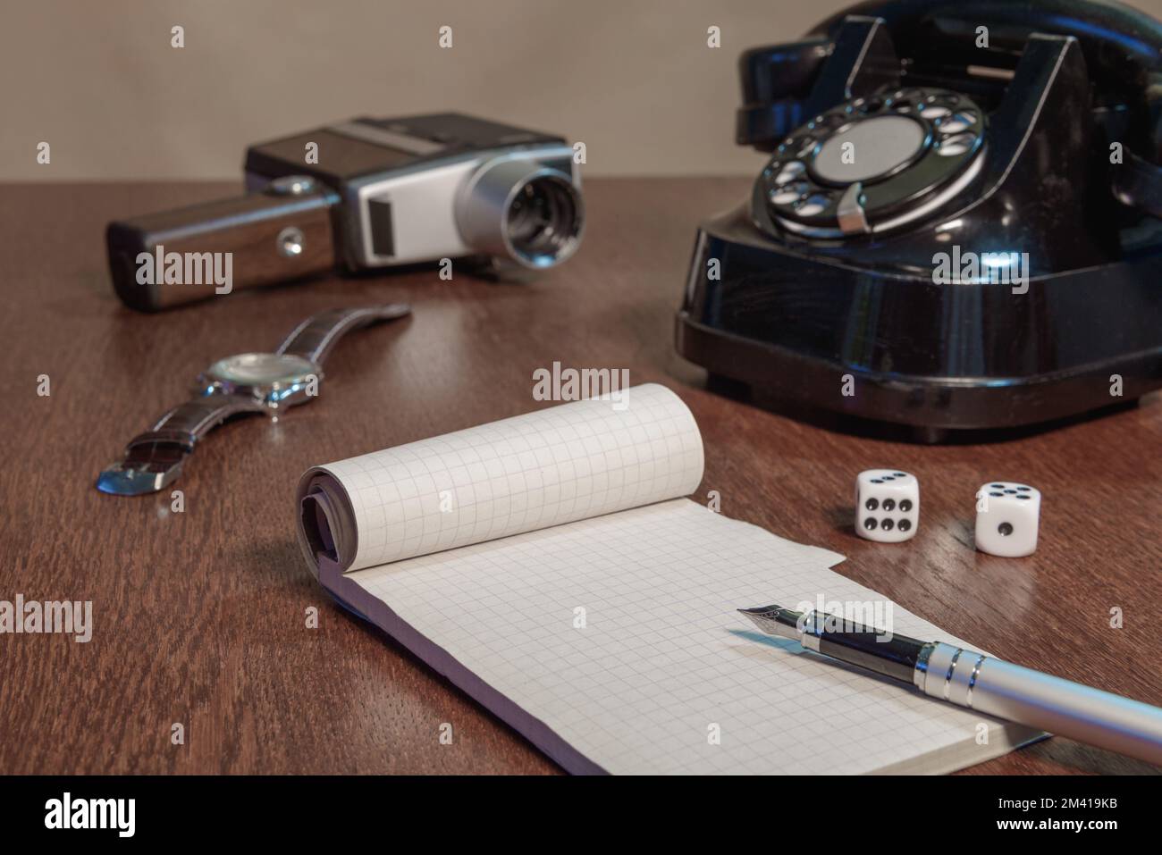 Notizbuch und Stift, auf dem Hintergrund von Armbanduhr, Würfeln, altem Telefon und alter Filmkamera Stockfoto