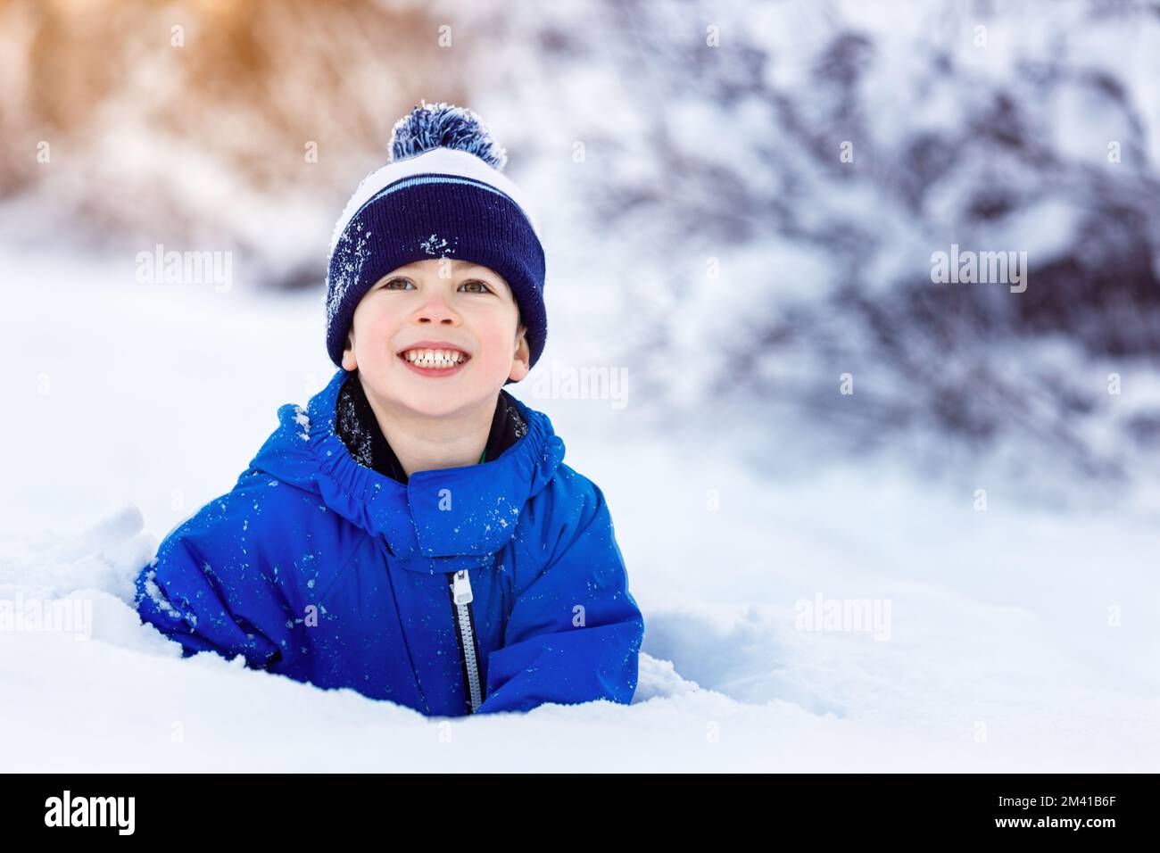 Süßer kleiner Junge, der Spaß im Schnee hat Stockfoto
