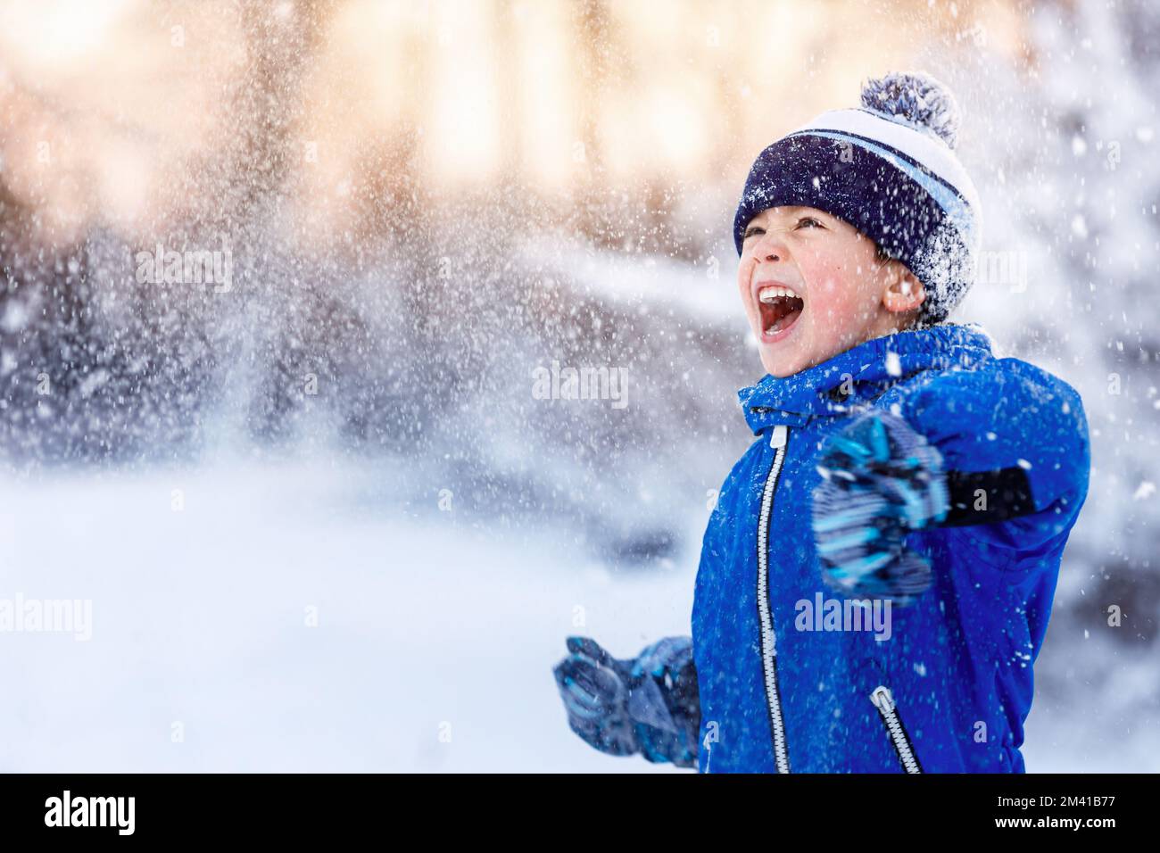 Glücklicher kleiner Junge, der Spaß im Schnee hat Stockfoto