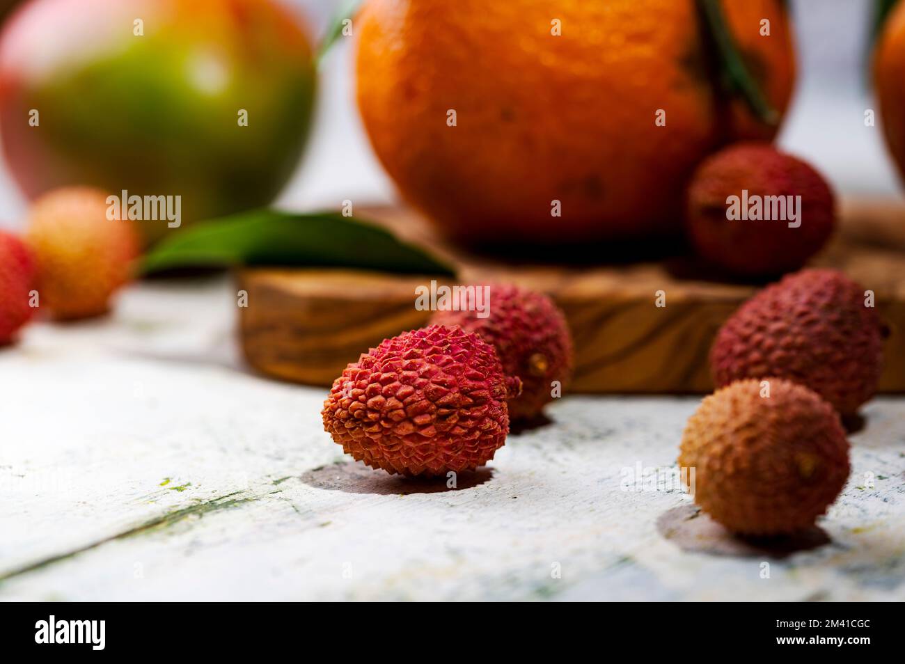 Ein Stillleben mit Lychees-Tangerinen und Mangos auf dem schäbigen Tisch Stockfoto