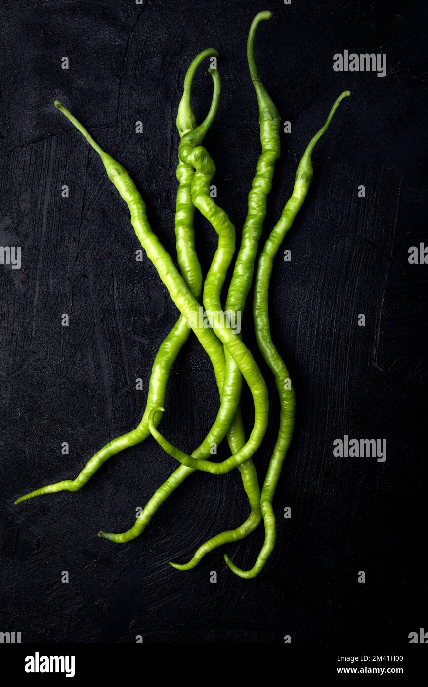 Ein Haufen reifer grüner Paprika auf schwarzem Hintergrund. Grüne, lange, heiße Paprika auf dunklem Hintergrund. Draufsicht. Speicherplatz kopieren. Stockfoto